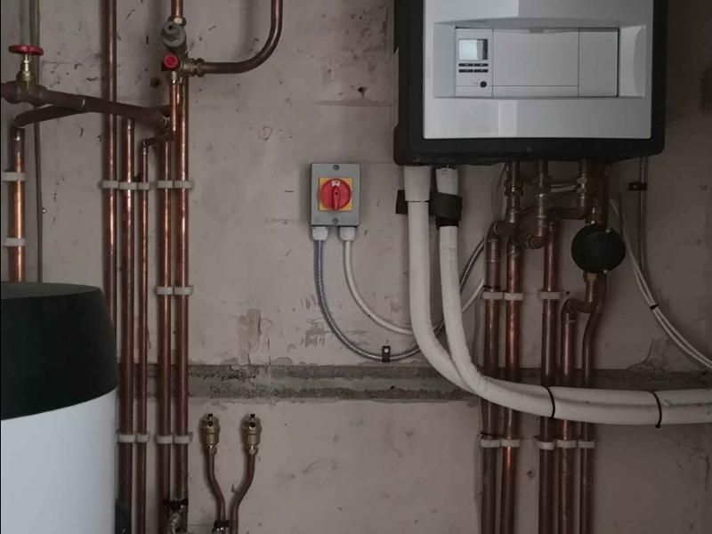Wall-hung boiler with copper pipework beside a hot water cylinder